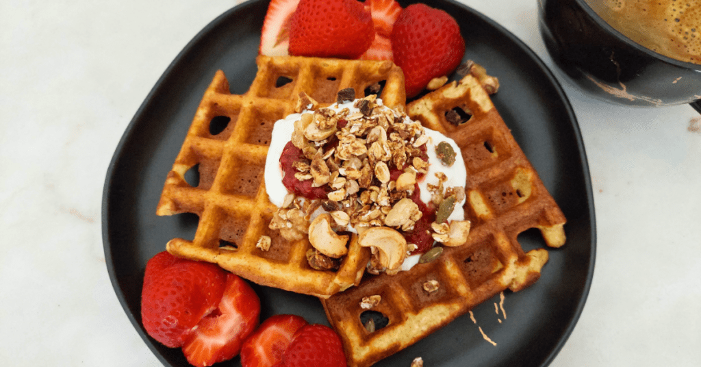 Deliciosas ideias do dia Waffles de coco com topping de queijo quark, doce de morango, granola e morangos.