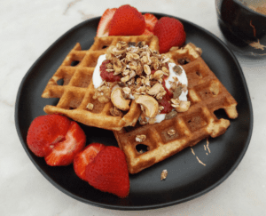 Waffles de coco com topping de queijo quark, doce de morango, granola e morangos.