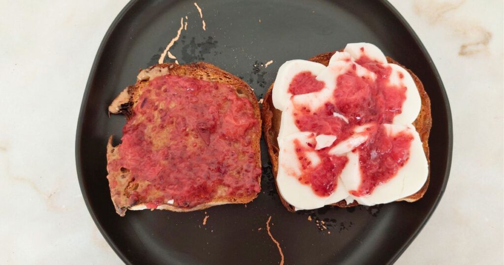 Lanche Torradas com manteiga de amêndoa e com queijo fresco e doce de morango.